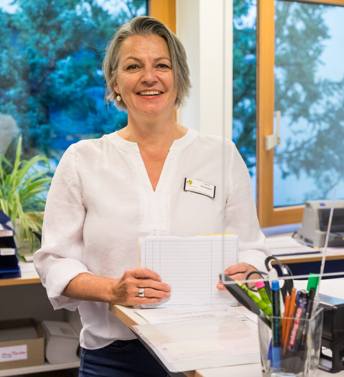 Foto am Schreibtisch der lächelnden Ambulanzsekretärin Carola Schneider der Neurologie.