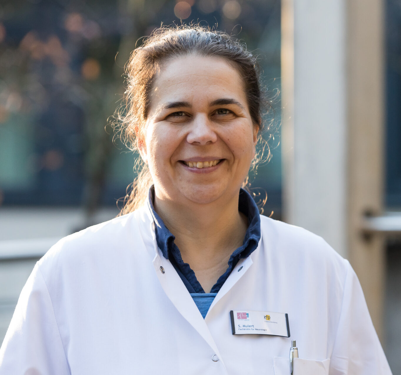 Portrait of the smiling doctor Susanne Mulert in a white doctor's coat.