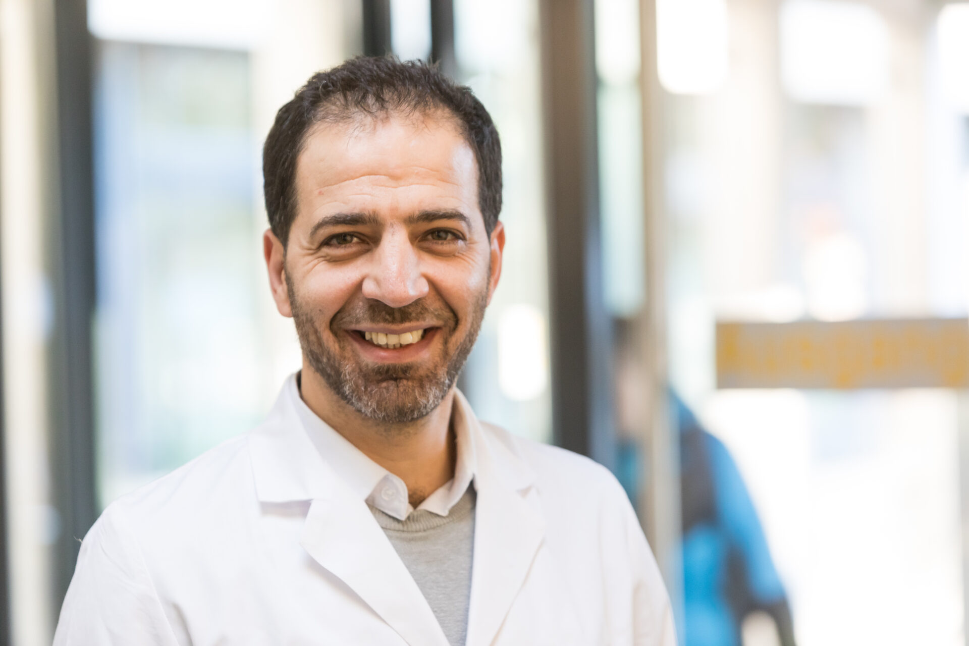 Porträt des lächelnden Arztes Hassan Seklawi in weißem Arztkittel.