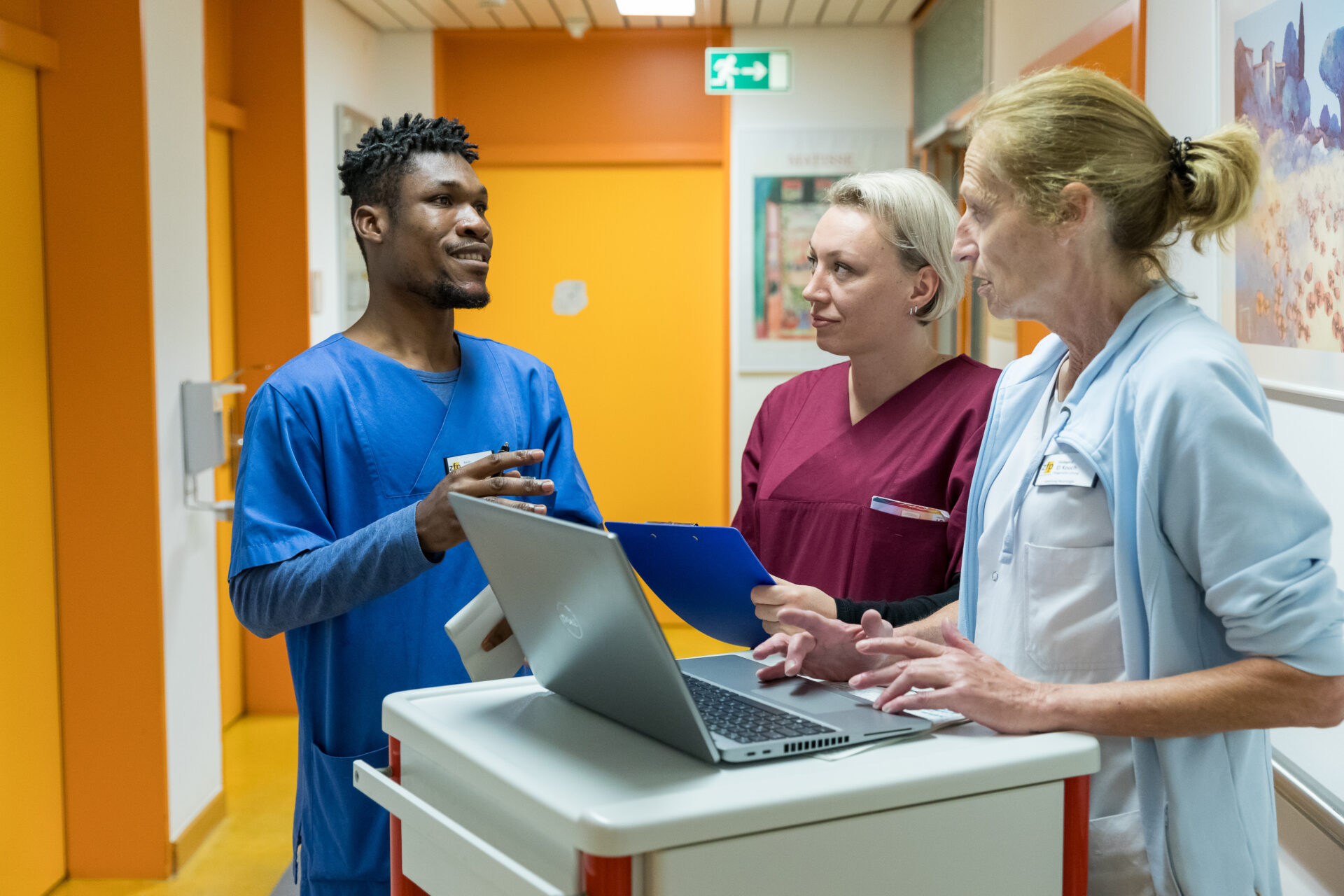 Medizinisches Team bespricht Patientendaten am Laptop in Krankenhausflur.